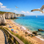 A scenic view of Thanet's coastline featuring chalk cliffs, a sandy beach, boardwalk, and seagulls.